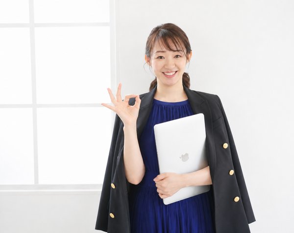 OKサインをしてノートPCを持つ、ビジネスシーンの古田あかねさんの写真